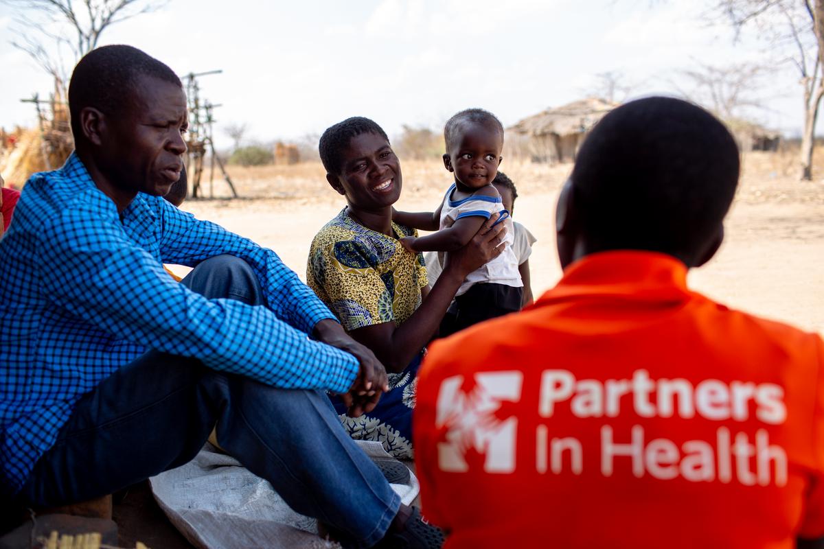 A community health worker shows educational material to a family, including a verbal TB screening.